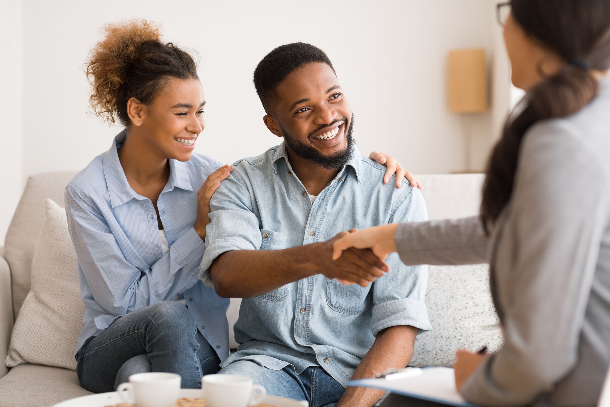 A happy couple engages in a welcoming conversation while shaking hands with a counselor, suggesting a session focused on relationship guidance.